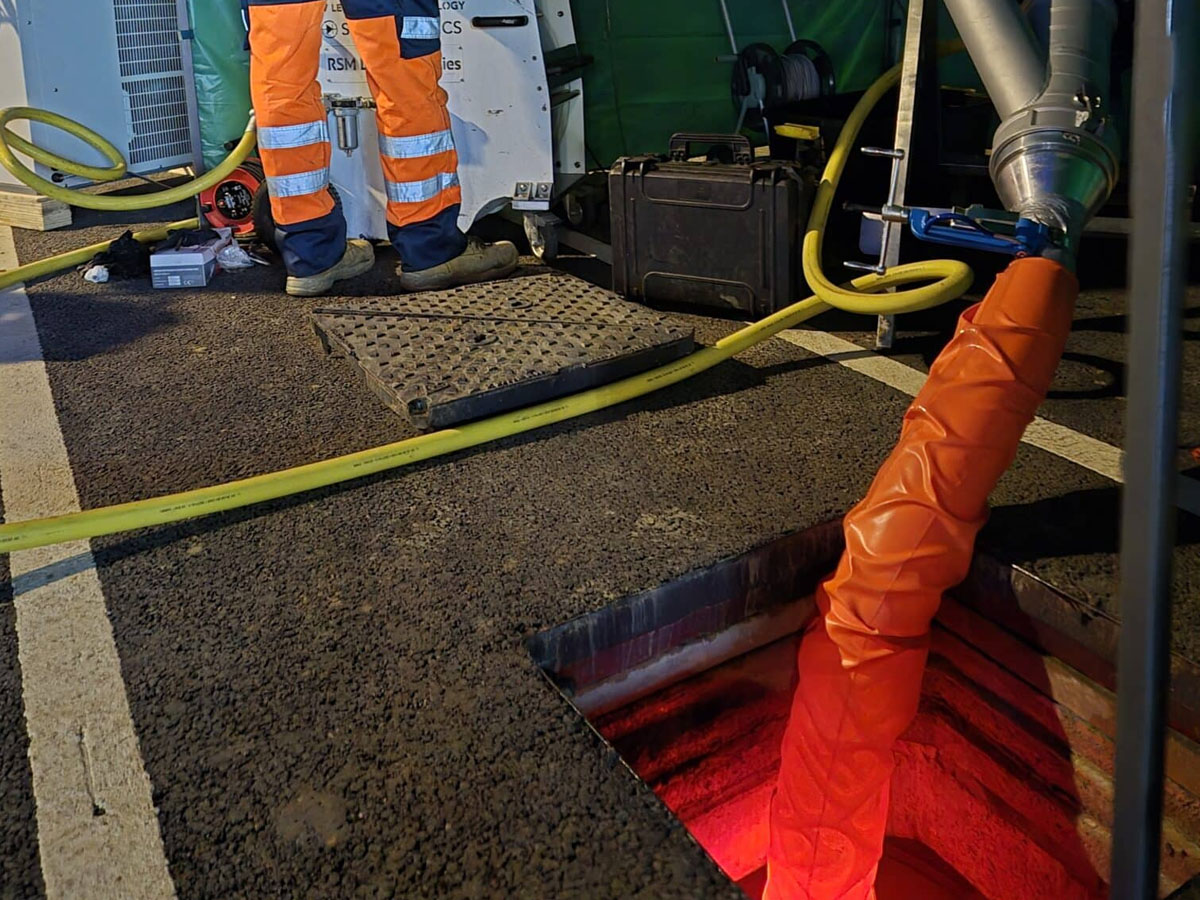 Close-up of an orange UV liner being inserted into a manhole for a trenchless pipe repair.