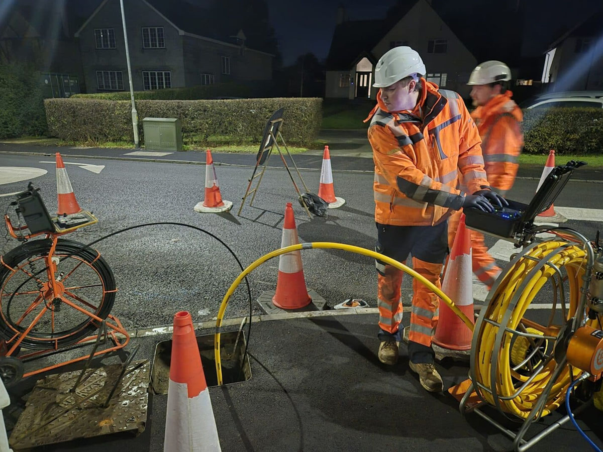 ngineer operating a robotic drain cutter with the cable feeding down an open manhole.